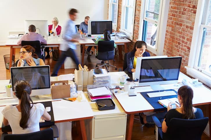 A diverse group of professionals collaborating in a modern office environment, focused on their tasks and discussions.
