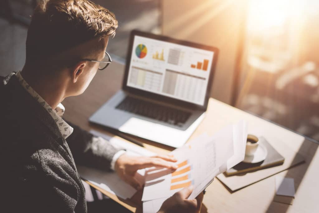 Man analysing investment graphs on a laptop, focused on data trends and financial performance.