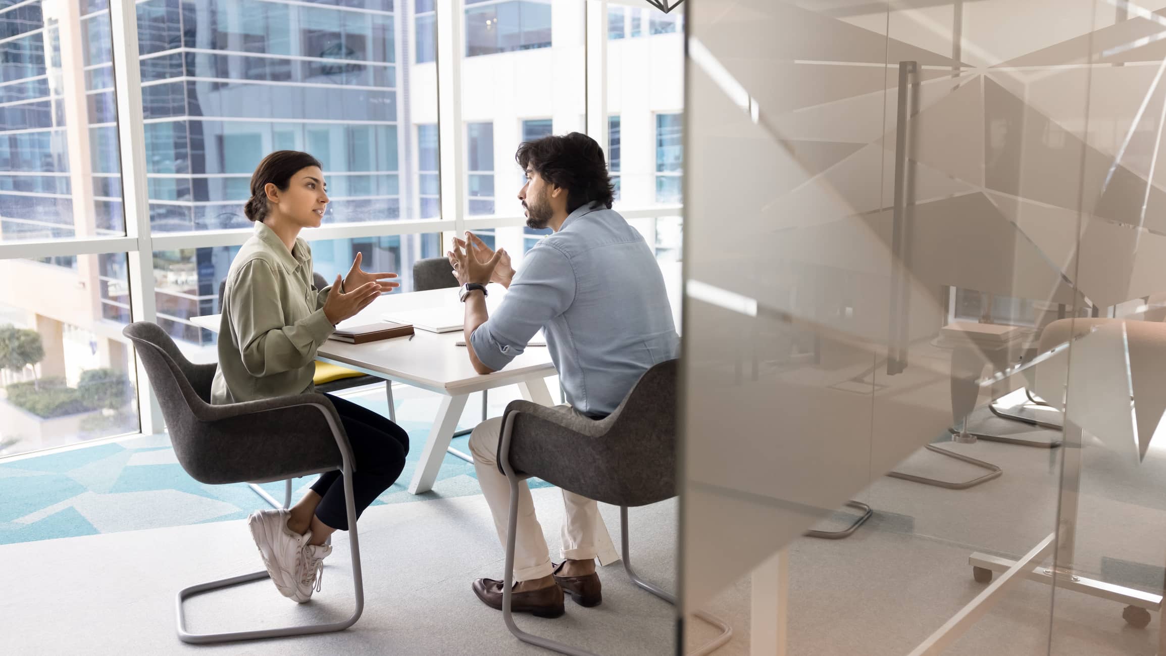 Two employees meeting in a modern office to discuss a workplace issue, representing performance management, employee relations and unfair dismissal processes for employers.
