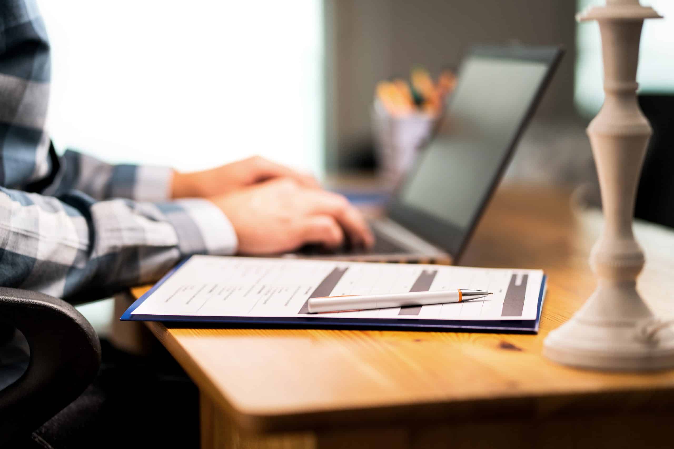 Survey form, customer satisfaction feedback poll, resume for job application or for college. Man writing with laptop. Home or car insurance contract. Paper sheet and pen on desk.
