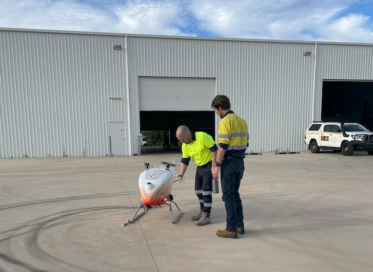 Two men standing around a white helicopter.