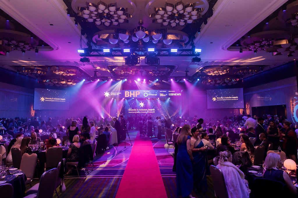 A brightly lit event hall with a stage, red carpet, dining tables, and the BHP and Siemens logos projected on screens at the Australian Mining Prospect Awards ceremony.
