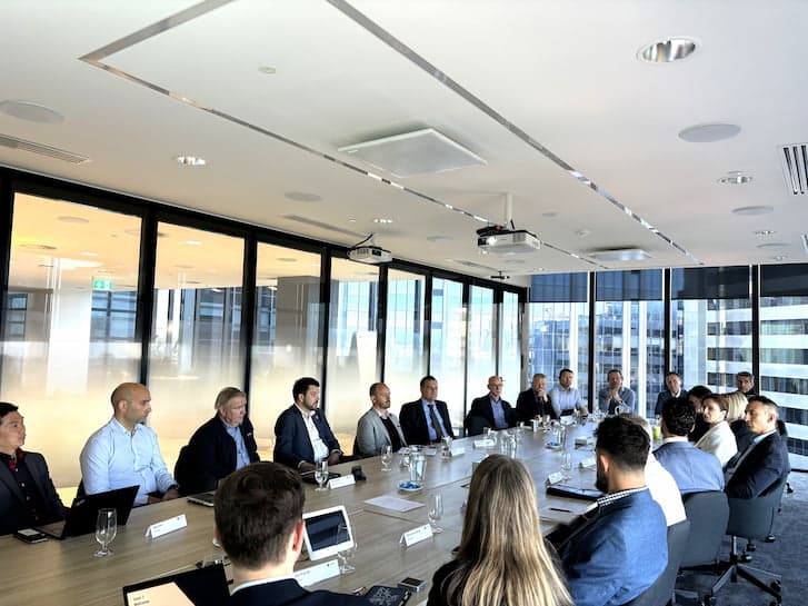 Several individuals seated at a conference table, actively participating in a meeting within a modern conference room.