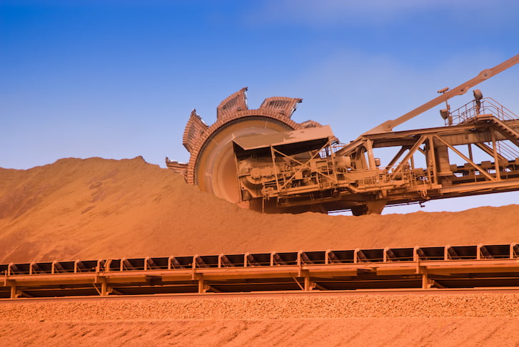 A large machine is transporting iron ore on a mine site.