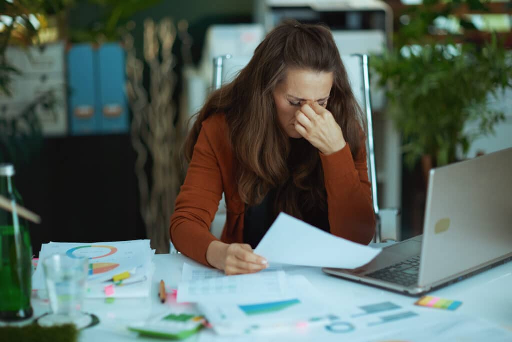 stressed modern small business owner woman with laptop working with documents.