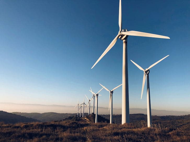 A cluster of wind turbines atop a hill, symbolising the use of wind energy for renewable electricity.