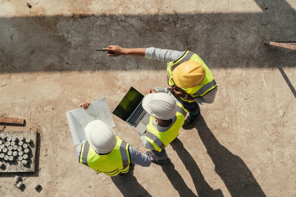 Top view, Team engineer building inspection use tablet computer and blueprint working at construction site. Civil Engineer, Contractor and Architect discussing in construction site.