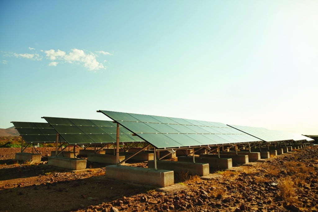 Solar panels installed in a vast desert field under a clear blue sky, harnessing renewable energy from the sun.
