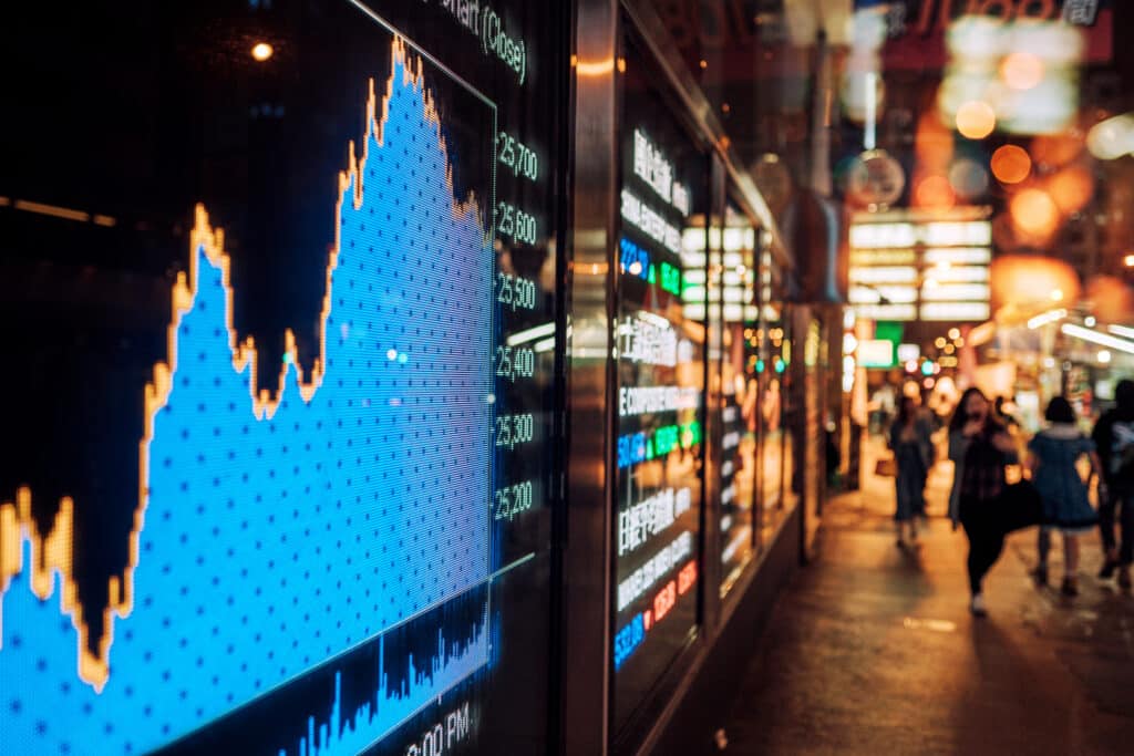 Stock market chart displayed on a screen, with a city skyline in the background, symbolising international trade and finance.