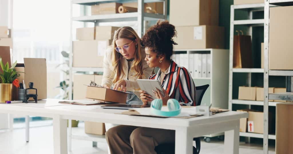 Women, tablet and teamwork for office logistics, package and e-commerce checklist with stock of online shop. Small business people or seller with digital tech, box and clipboard for website order