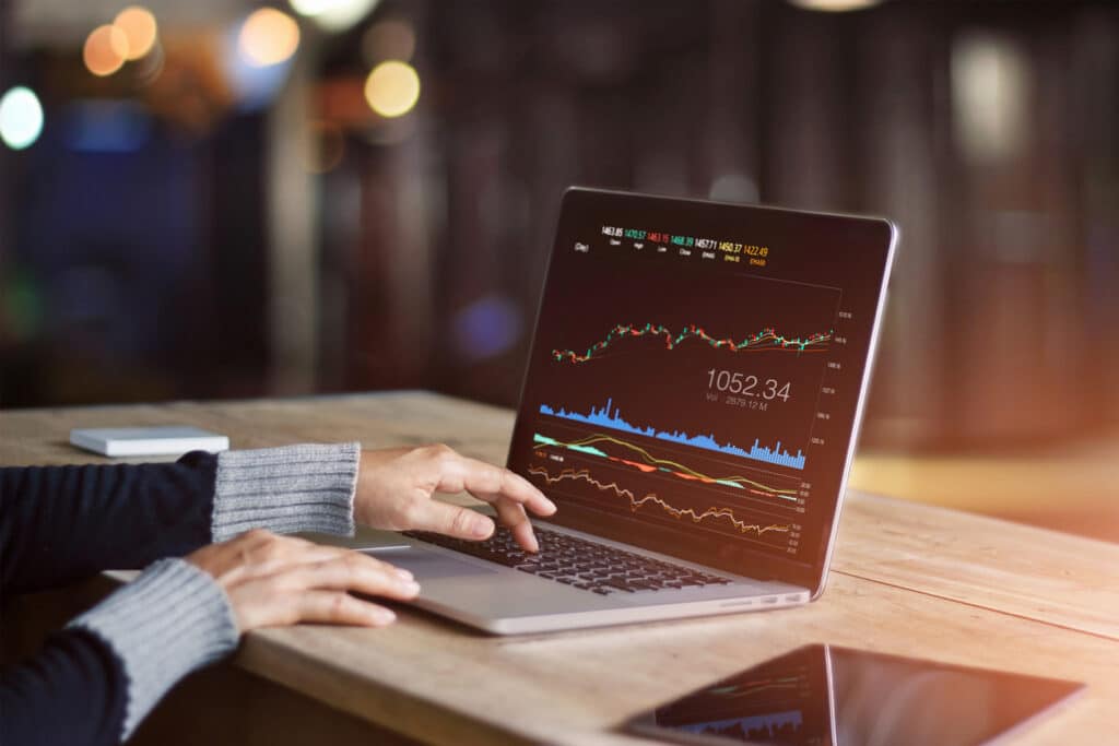 Person using a laptop displaying financial market charts and data, representing global trade, export performance and economic analysis.