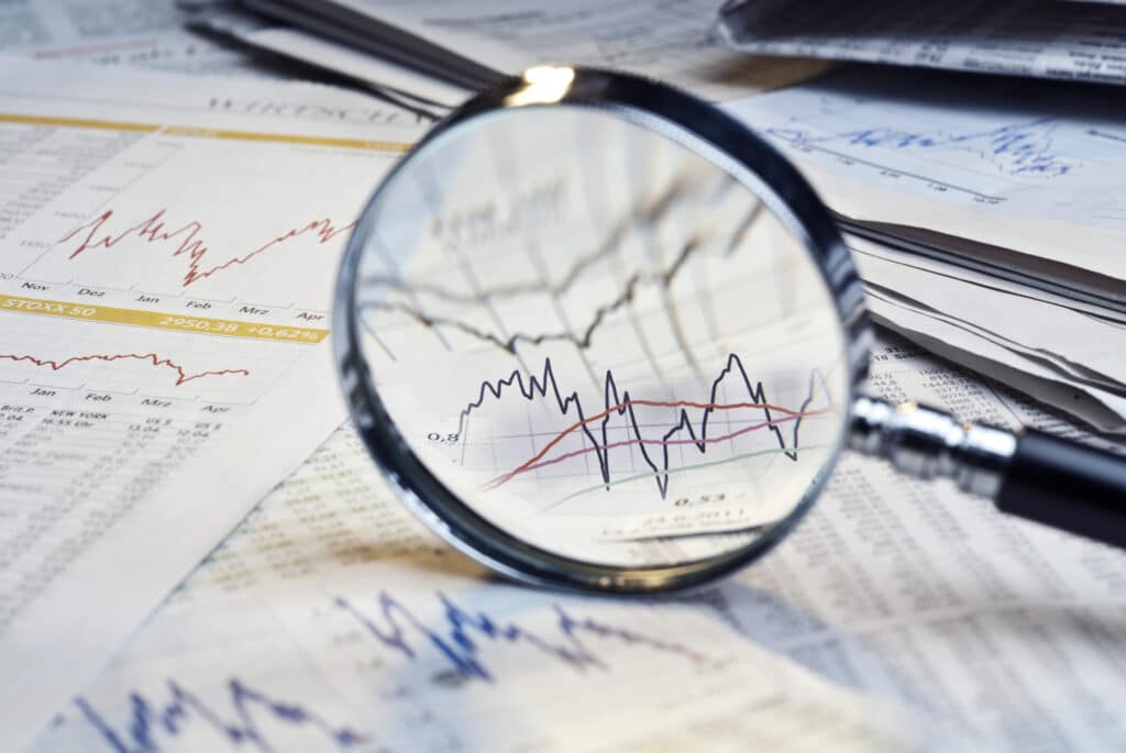Magnifying glass resting on financial documents, highlighting details related to investment risk analysis.