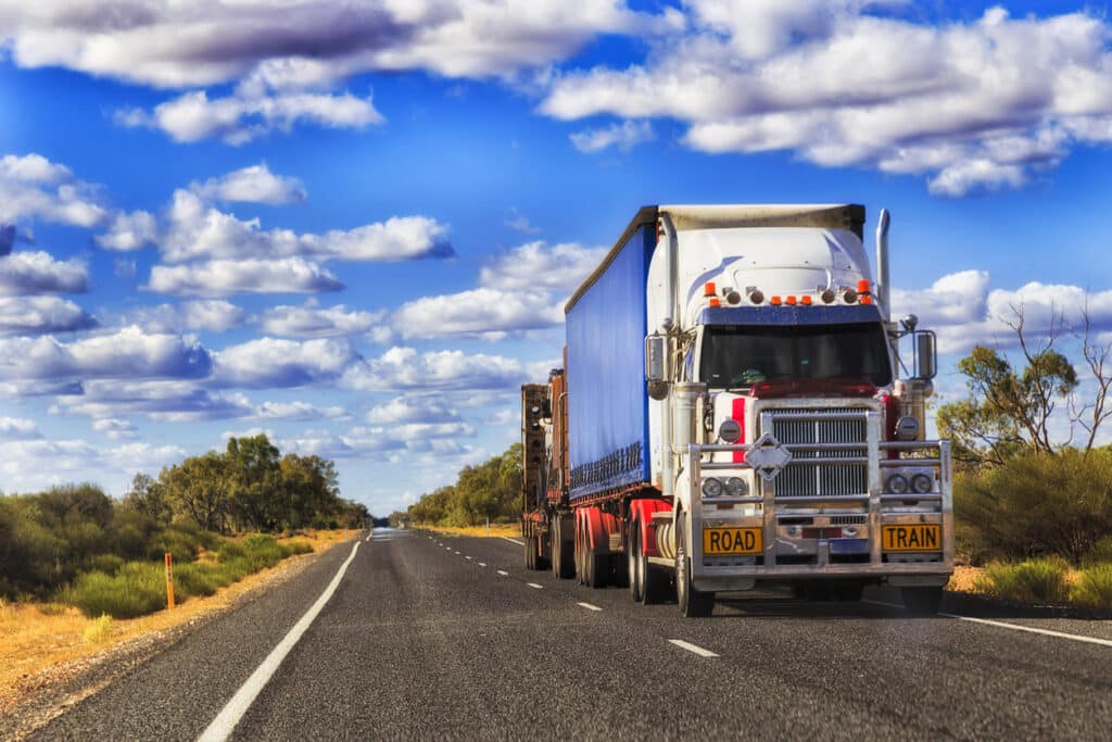 Road train truck travelling along a regional highway, representing long-haul transport, regional logistics and freight distribution across Western Australia.