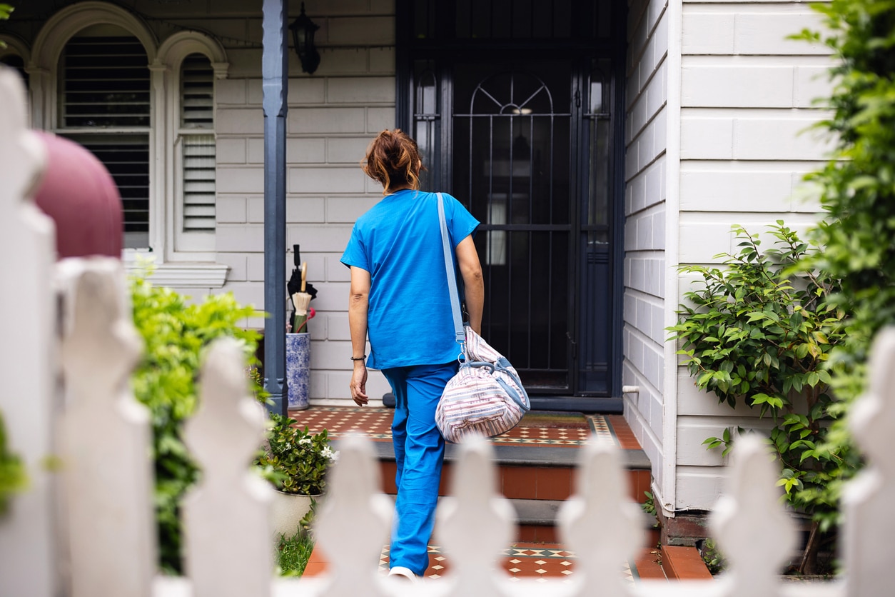 Healthcare worker arriving at a client’s home carrying a bag, representing in-home care services, disability support and community-based healthcare work.
