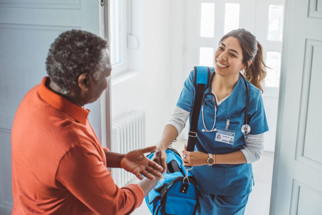 Community healthcare worker greeting a client at their home, representing SCHADS Award employment, in-home care services and disability support work.
