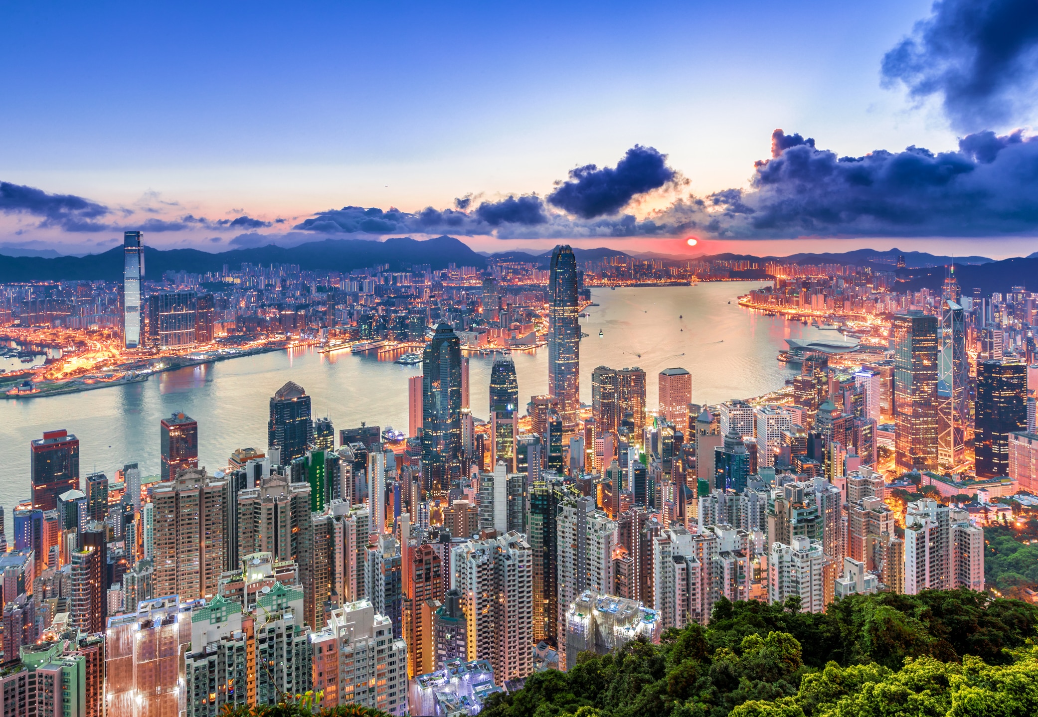 Hong Kong skyline at sunset overlooking Victoria Harbour, showcasing the city’s dense urban landscape, international business hub status and role as a gateway to Asian trade and investment.