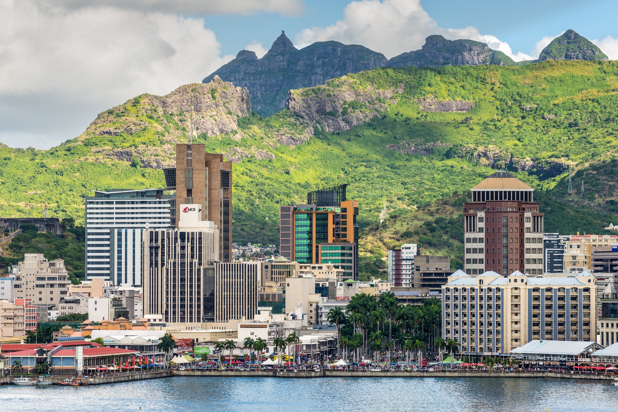 City skyline and waterfront of Mauritius with modern office towers set against lush green mountains, representing international business, trade and investment in Mauritius.