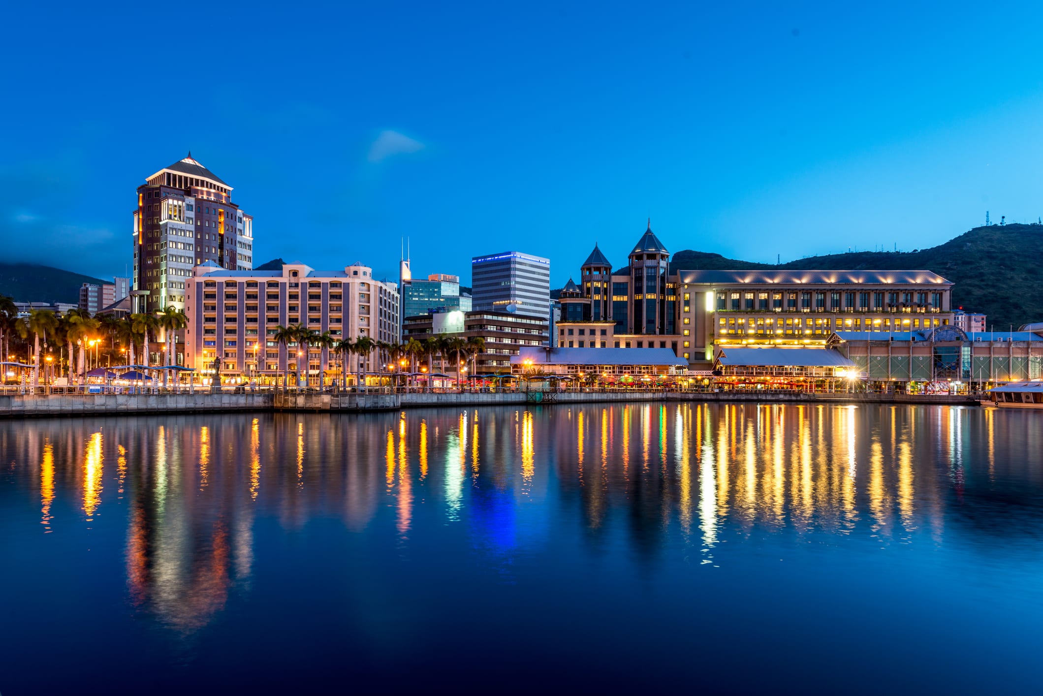 Waterfront skyline of Mauritius at dusk with illuminated buildings reflected on the harbour, representing international business, trade and investment opportunities in Mauritius.