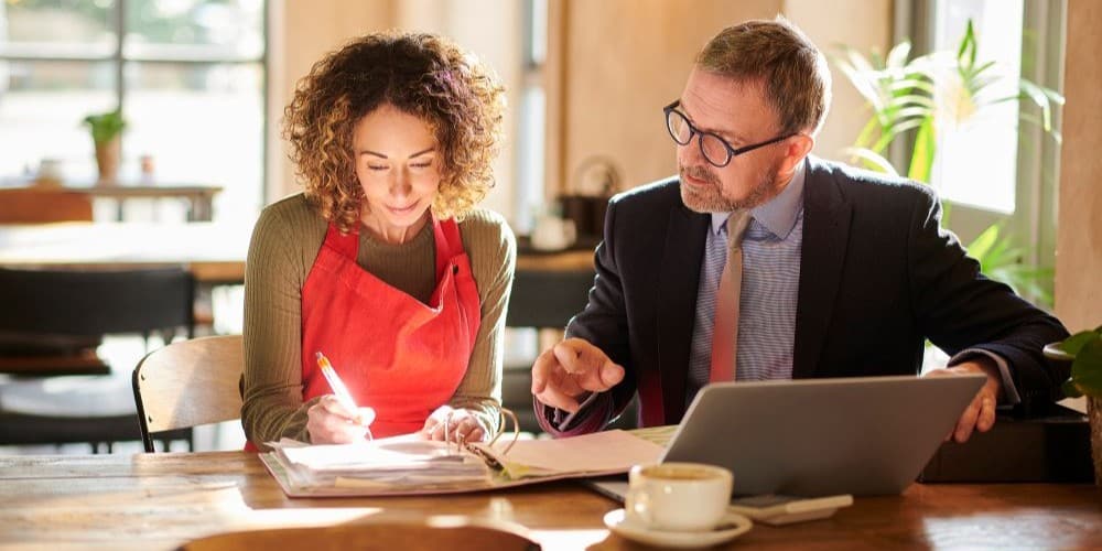 Small business owner meeting with a business adviser to review financial documents and accounts, representing small business planning, tax management and financial advice.