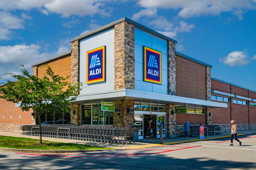 A customer approaches the front entrance of an Aldi grocery store.